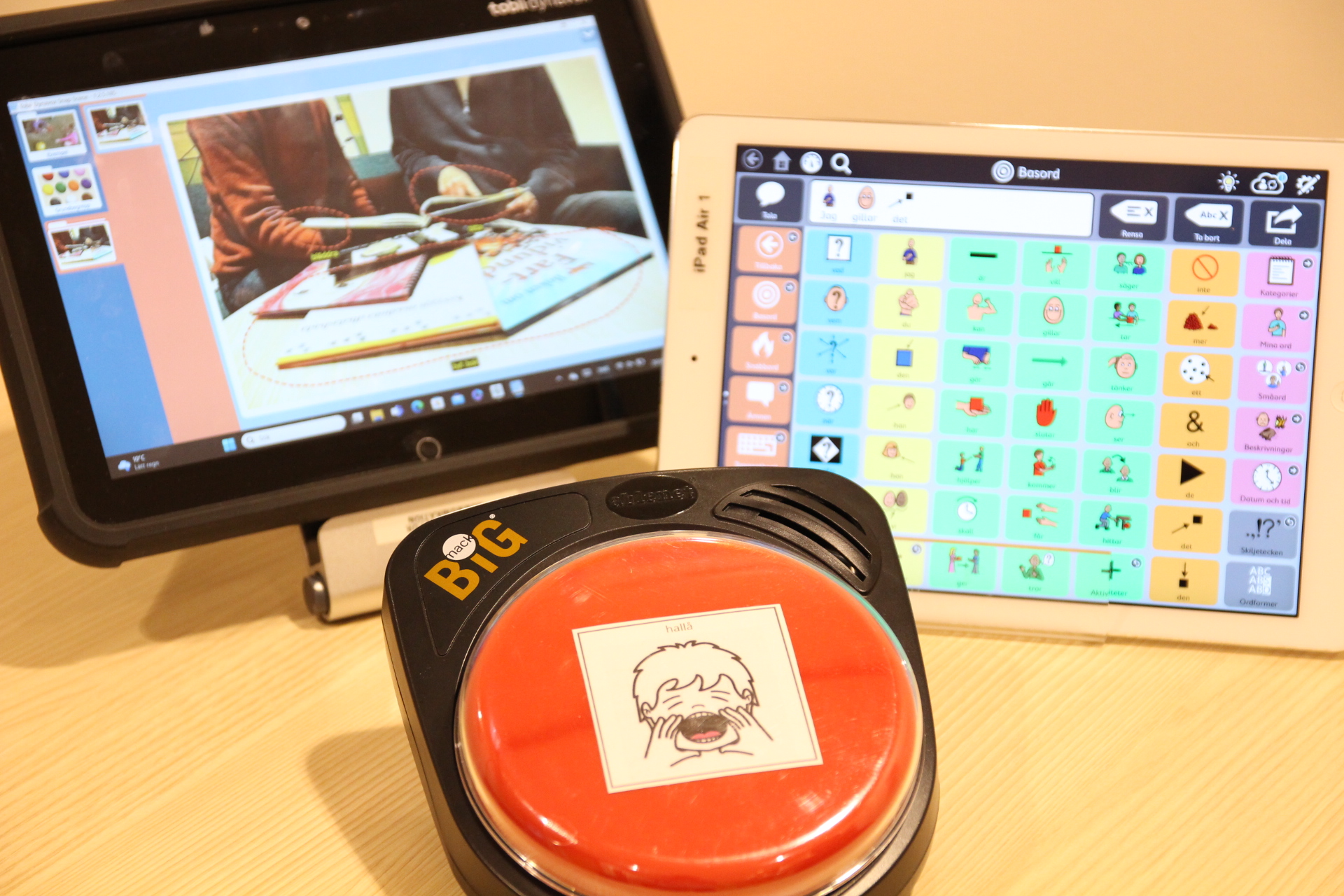 Två iPads med olika appar och en talknapp på ett bord